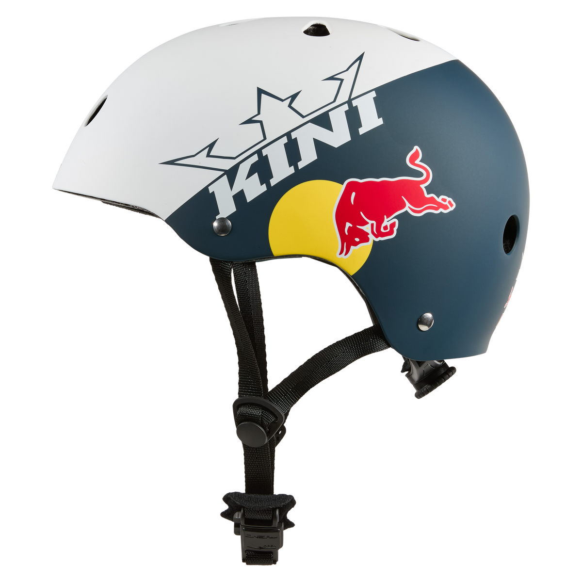 Der KINI RED BULL BB Helm 1.0 von Kini Red Bull ist ein blau-weißer Helm mit "KINI", Kronengrafik, gelbem Kreis und RED BULL Logo an der Seite. Er hat einen schwarzen Kinnriemen, Belüftungslöcher und sorgt für zuverlässige Sicherheit des Fahrers.