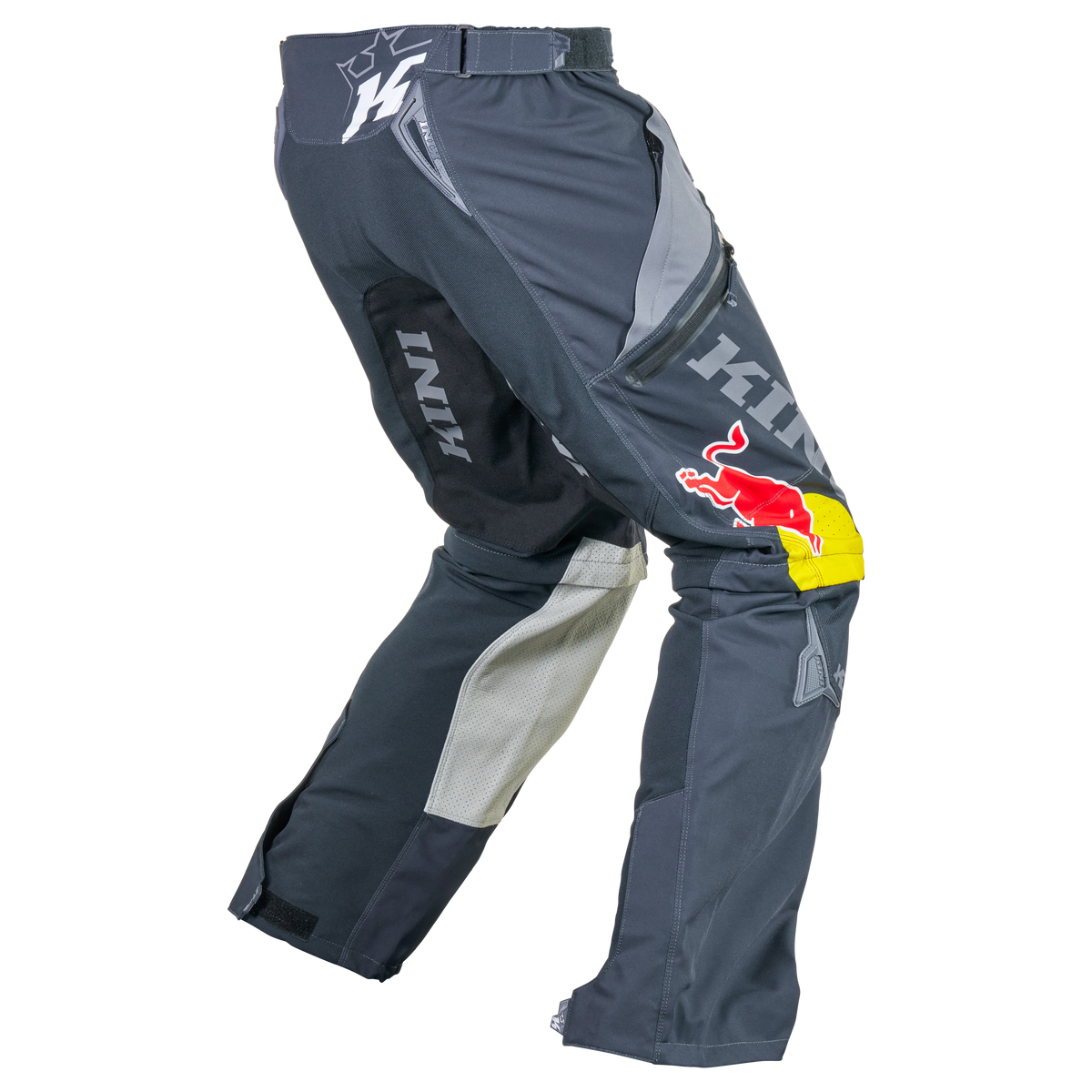 Ein Paar Kini Red Bull EXC X Hose 1.0 Motocross-Hosen in Schwarz und Grau, mit dem Red Bull-Logo auf dem rechten Oberschenkel und "HINI" auf der linken Seite, wird vor einem transparenten Hintergrund gezeigt. Marke: Kini Red Bull.