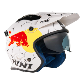 Der Mission Kini KINI RED BULL XDR 1.0 Helm ist ein weißer Motorradhelm mit sechseckigem Muster, Red Bull Logo, schwarzem "KINI"-Schriftzug, blau getöntem Visier und blauer Innenpolsterung.